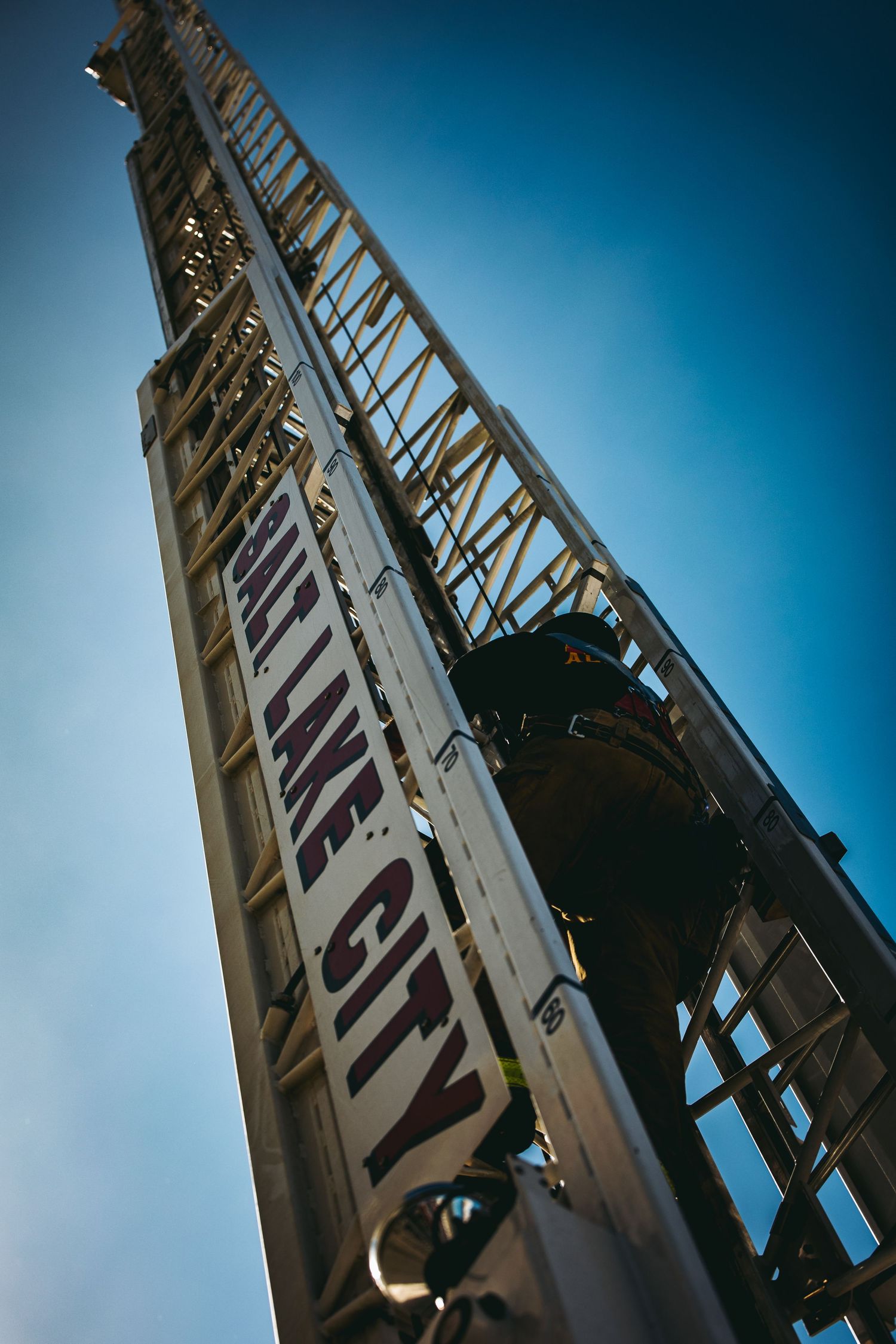Looking up at a tall white ladder extending into the blue sky against a dramatic angle.