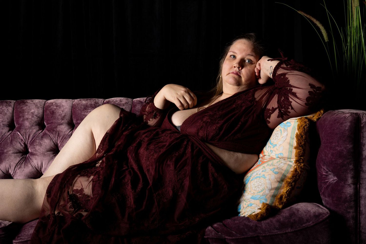 Romantic boudoir scene on purple velvet couch with soft lighting.