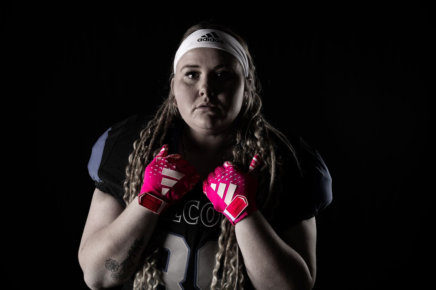 Athletic figure wearing pink boxing gloves in dramatic dark lighting.