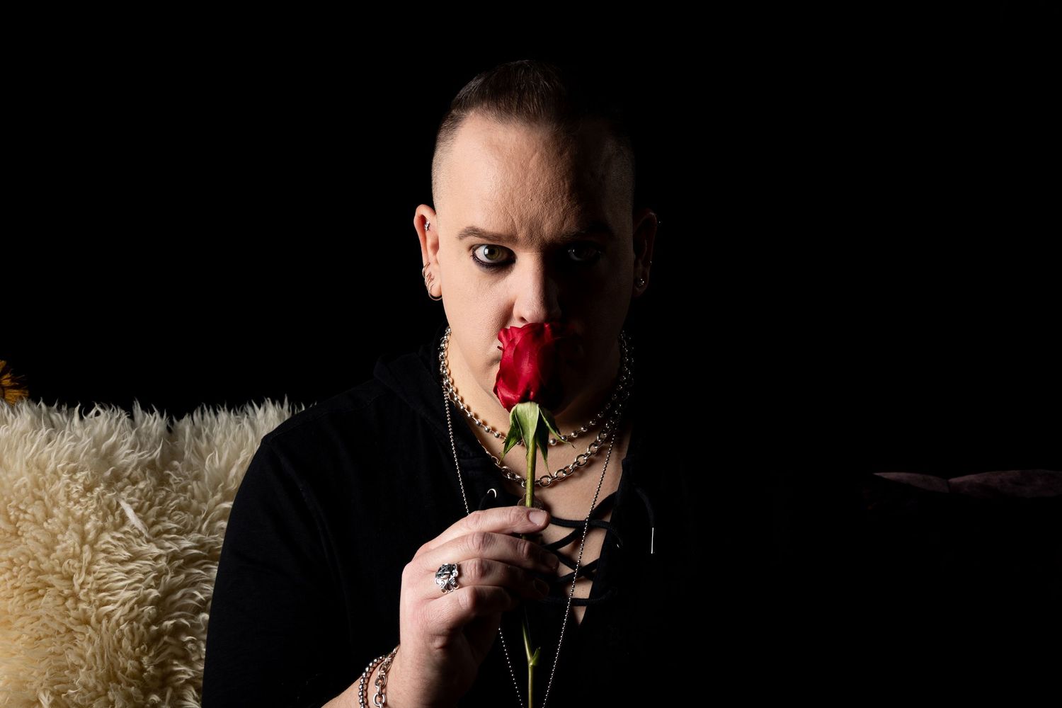 male with a red rose in a dark and moody setting.