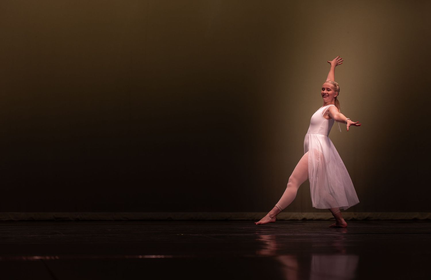Ballet dancers perform a graceful sequence in a dimly lit theater during a contemporary dance performance.