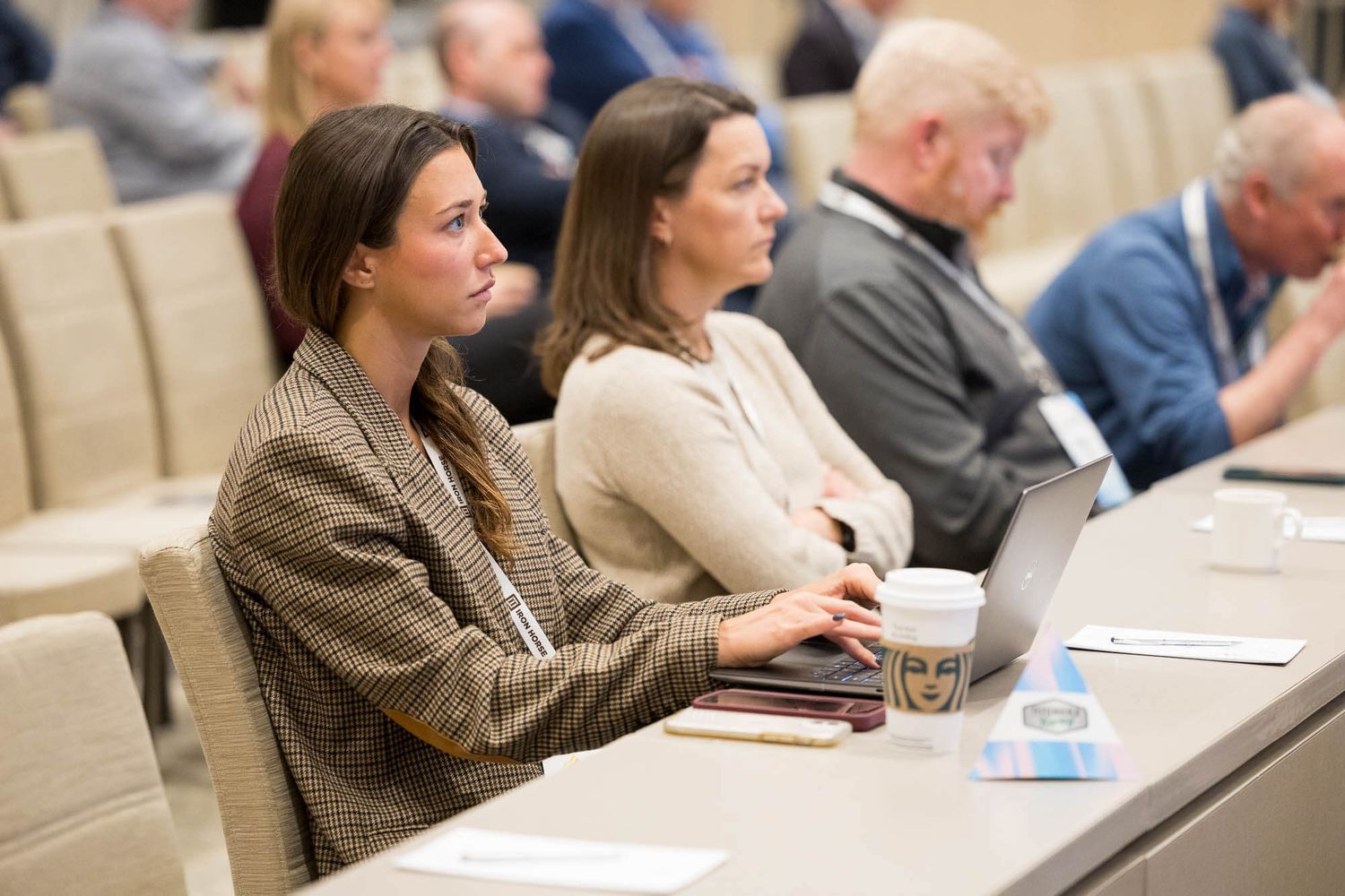 Woman in blazer uses laptop at conference table during professional seminar at the JW Marriott Parq Vancouver.