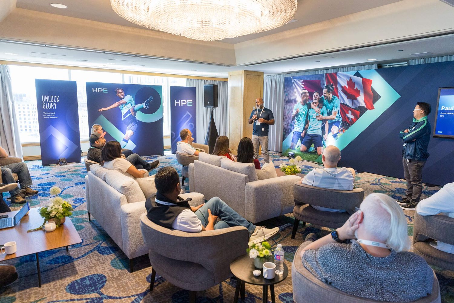Business audience engages with a speaker at an HPS branded corporate event in an upscale hotel lounge.
