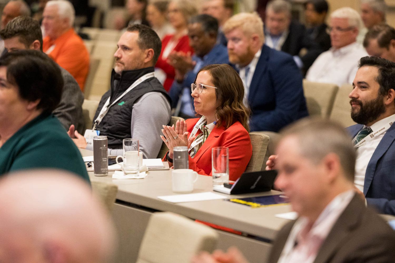 Engaged conference attendees including a woman in red applauding during a professional business meeting event.