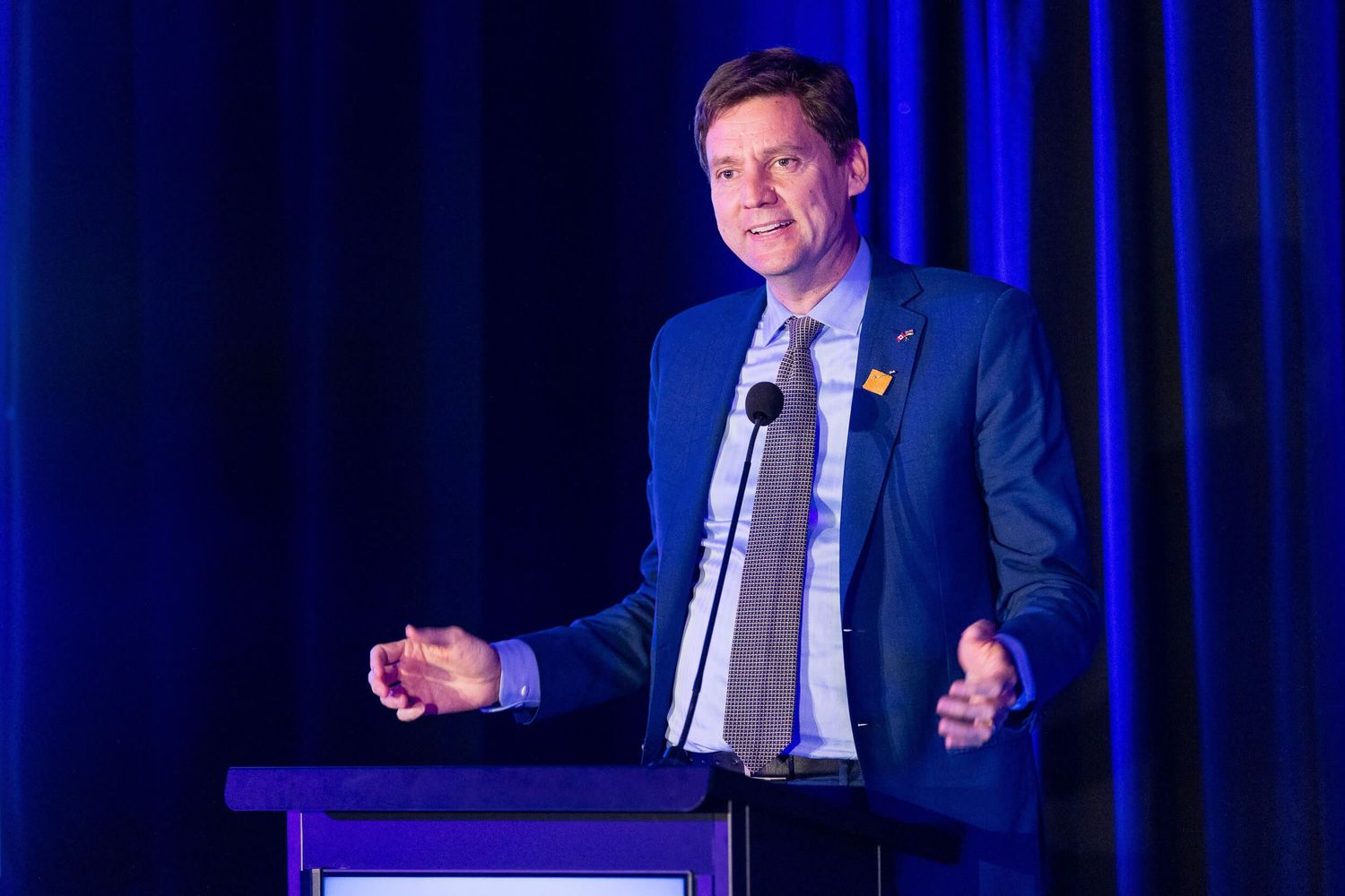 David Eby speaks speaks passionately at a podium during a professional conference event for BC College of Family Physicians.