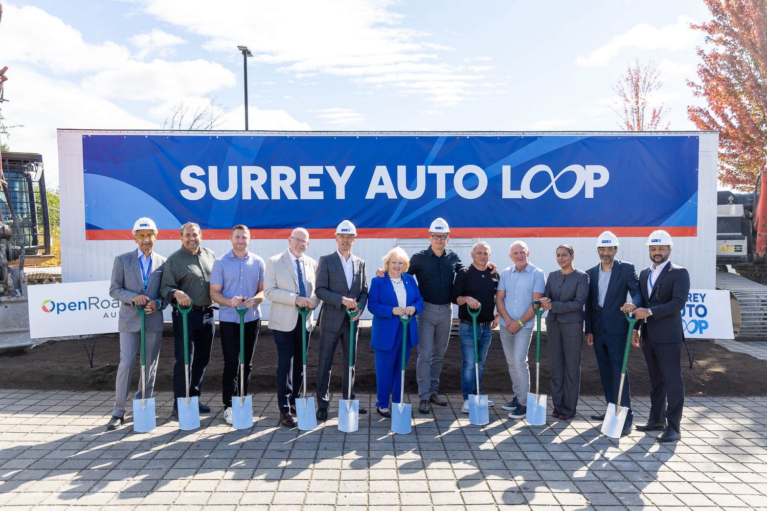Group of officials at Surrey Auto Loop groundbreaking ceremony, holding shovels in front of branded banner.