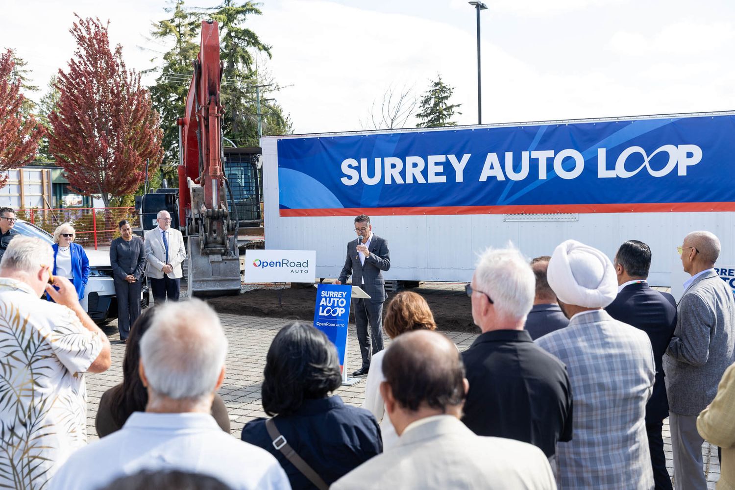 Official Surrey Auto Loop launch event with speaker addressing crowd near branded truck in Surrey, BC.