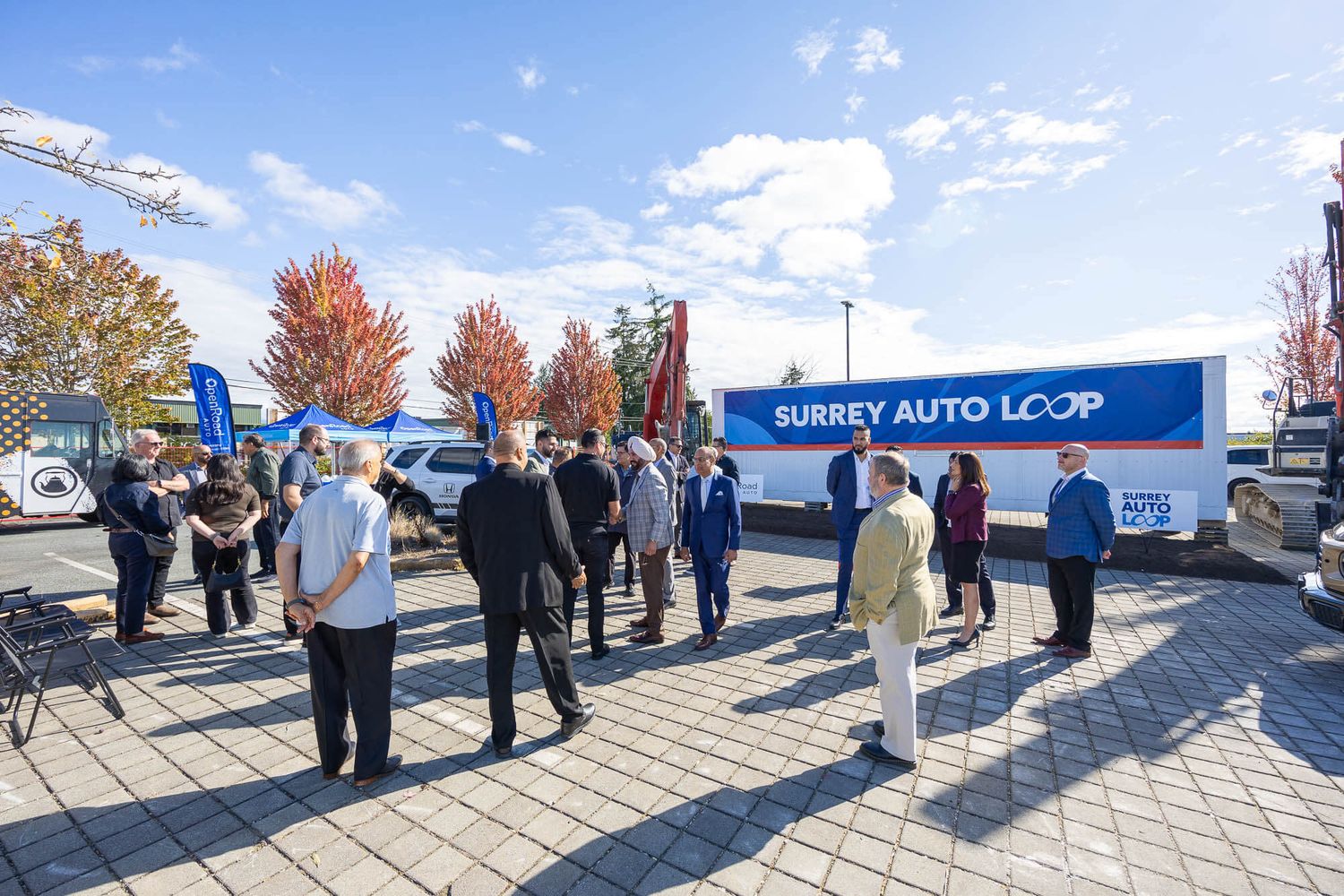 Surrey Auto Loop event with attendees gathered outdoors near a branded trailer on a sunny autumn day.