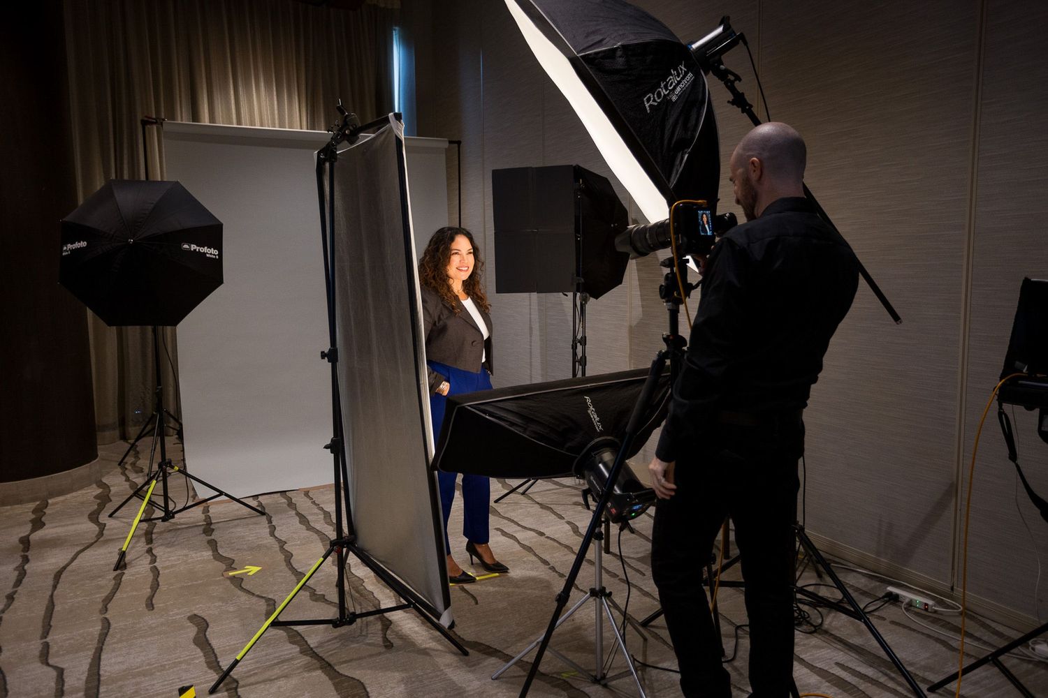 Professional headshot photography session with a woman posing before studio lights and white backdrop.