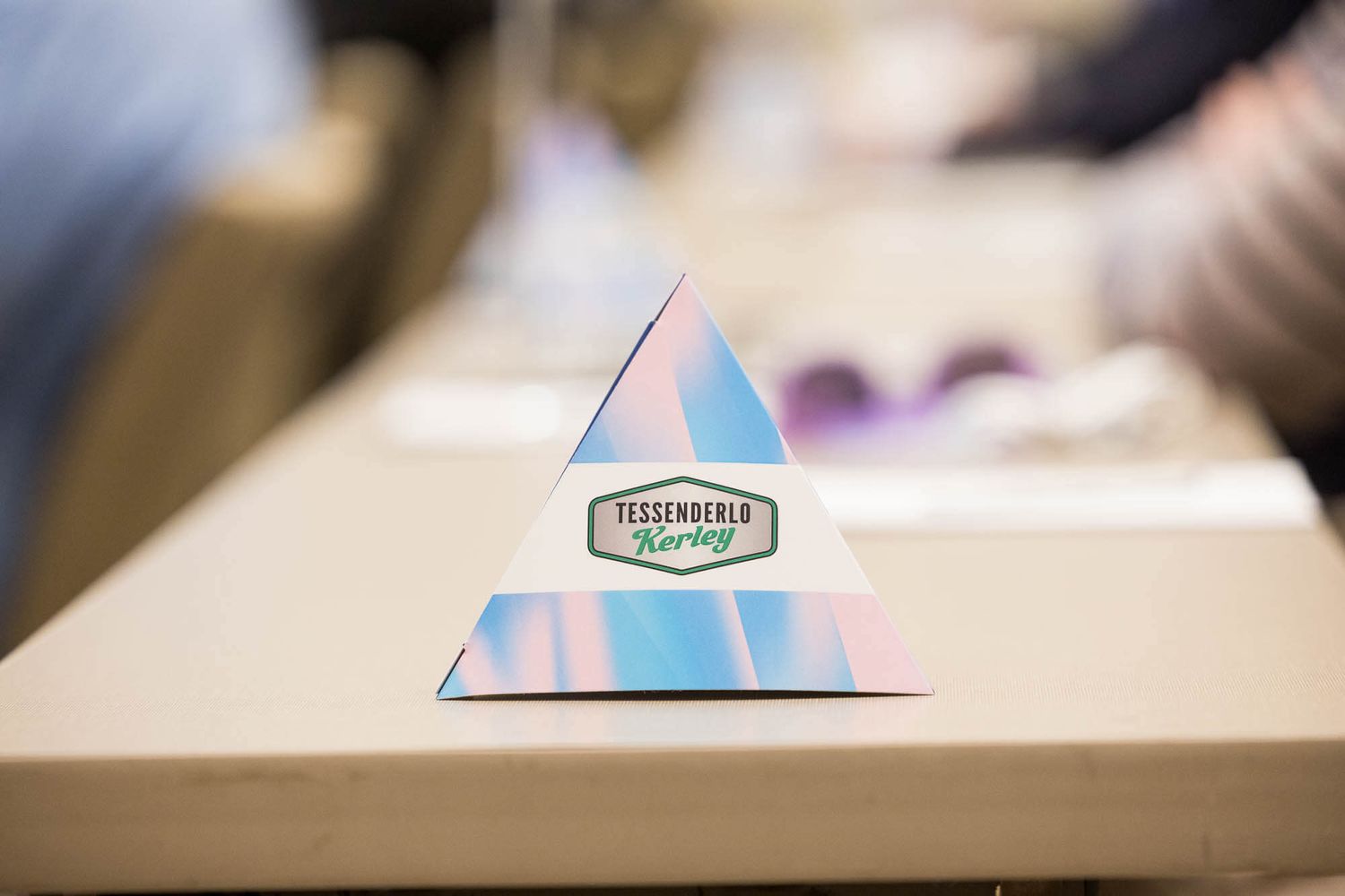 Triangular paper tent card with Tessenderlo Kerley logo displayed on a wooden table at a conference event at the JW Marriott Parq Vancouver.