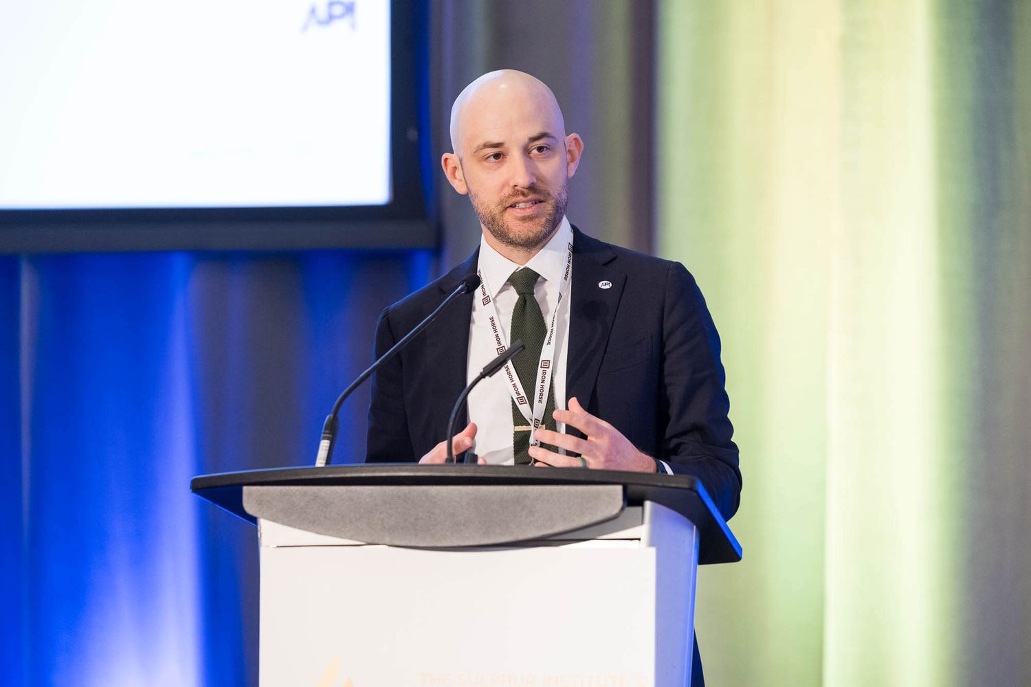 Professional man in dark suit speaking at a podium at the Sulphur Institute Conference held at the JW Marriott Parq Vancouver.