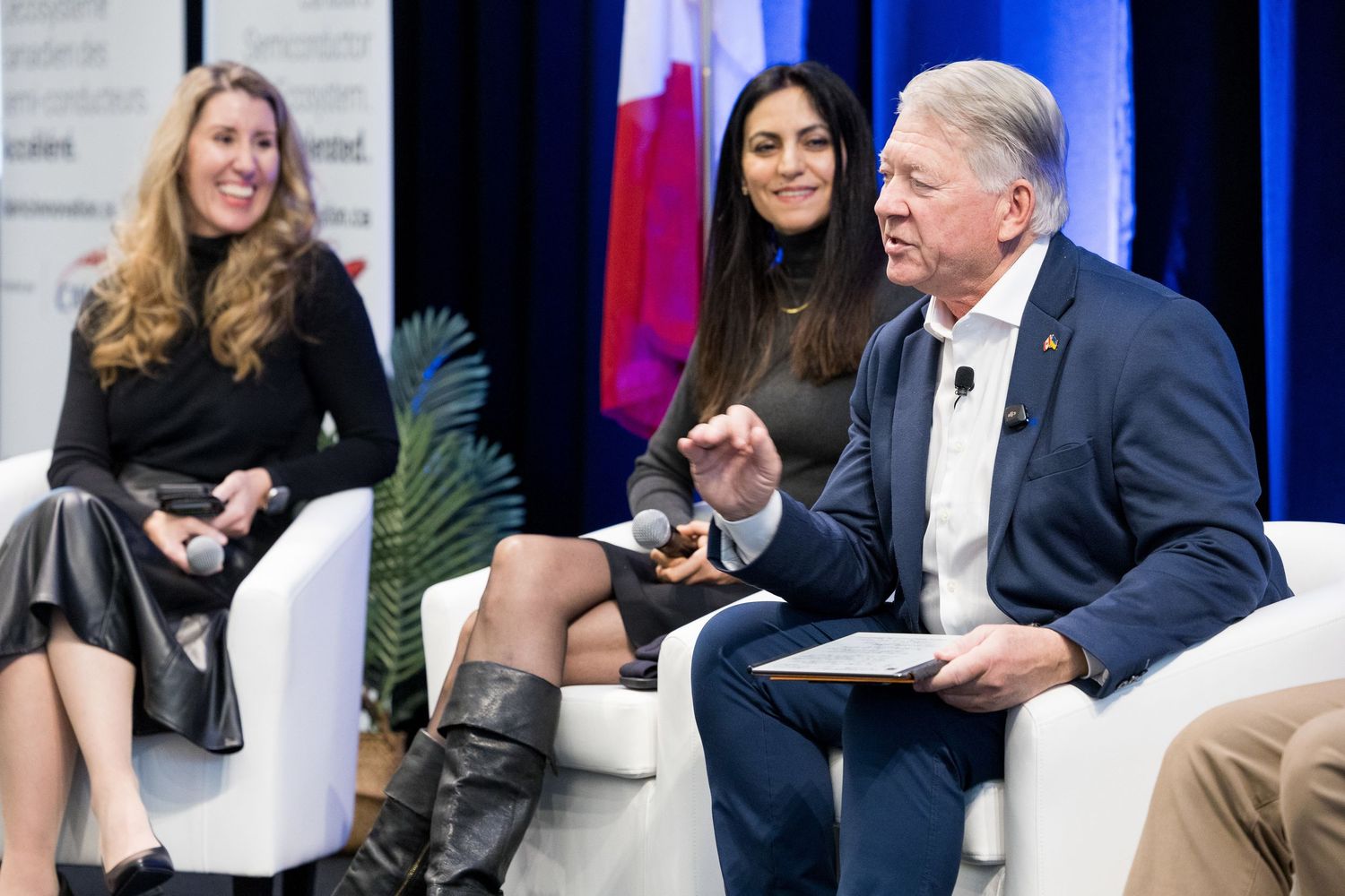 Three panelists seated on stage during a professional conference discussion event held at the Sheraton Wall Centre Vancouver.