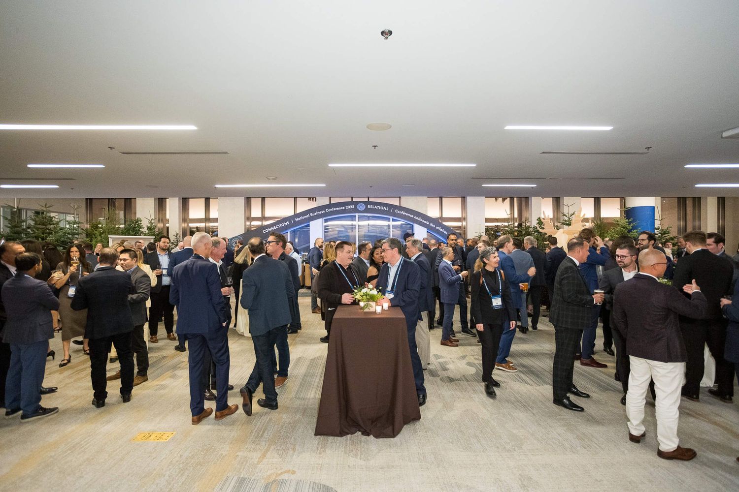 Business professionals networking at a corporate event in a modern conference venue lobby.