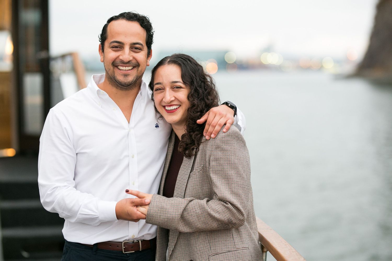 Smiling couple posing together outdoors on Pacific Yacht Charters, man in white shirt with arm around woman in gray blazer.