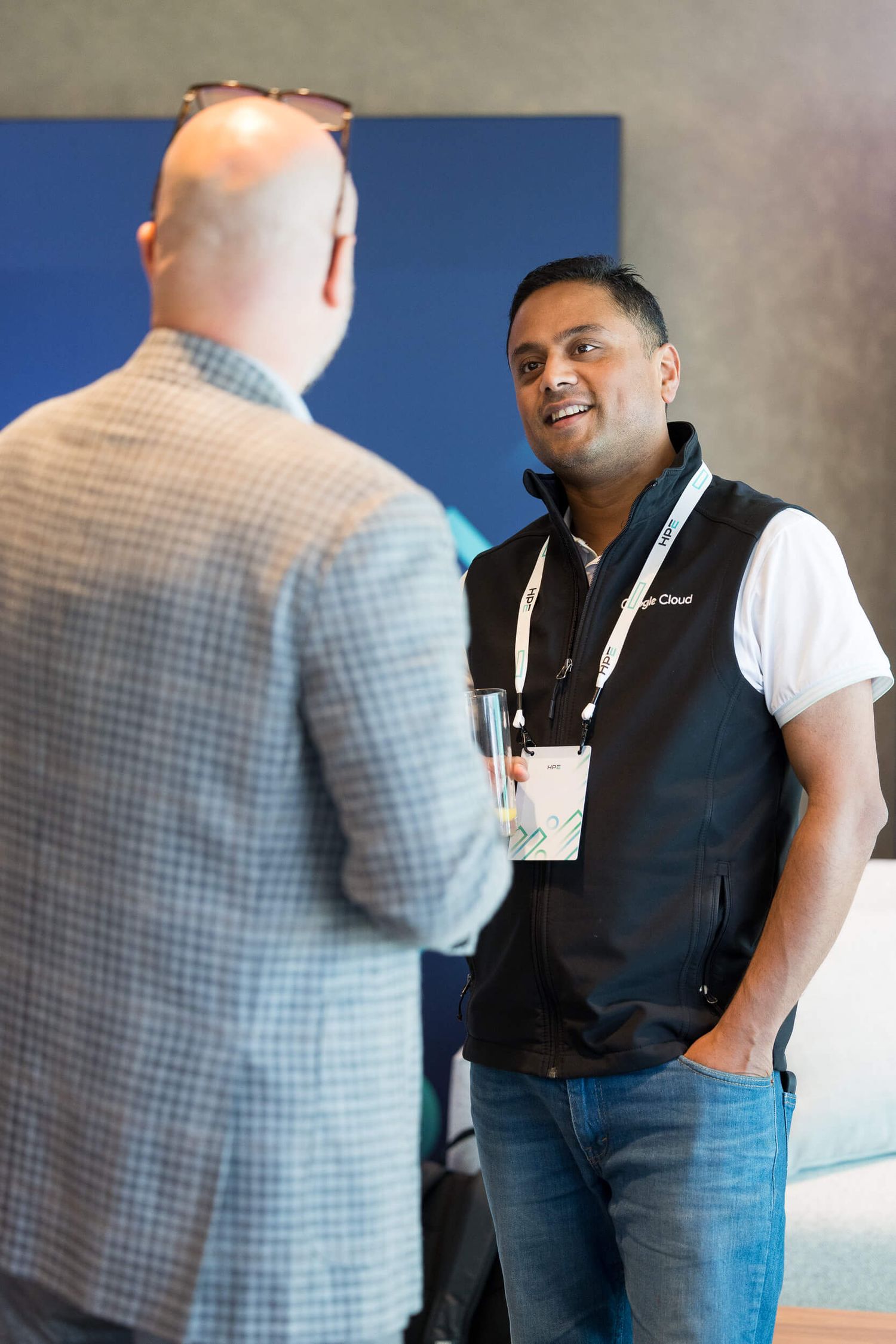Two professionals networking at a Google Cloud conference, smiling and conversing in a modern event venue.