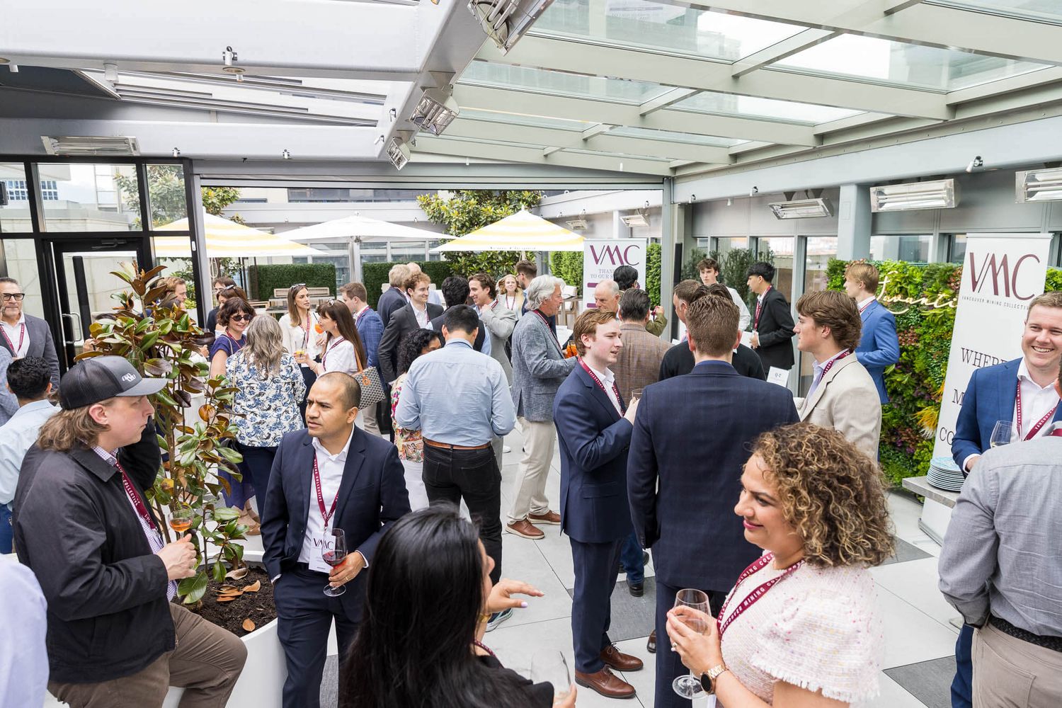 Professionals networking at an outdoor corporate event with white tents and modern venue backdrop.