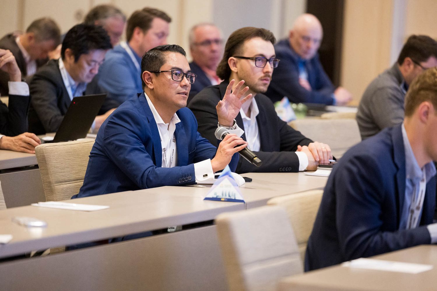 Business professionals engaged in discussion during a corporate conference session in a modern meeting room.