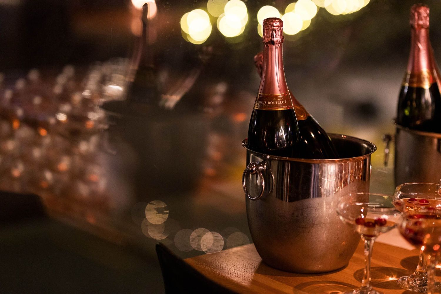 Champagne bottle chilling in an ice bucket with glasses on a table at an elegant evening event.