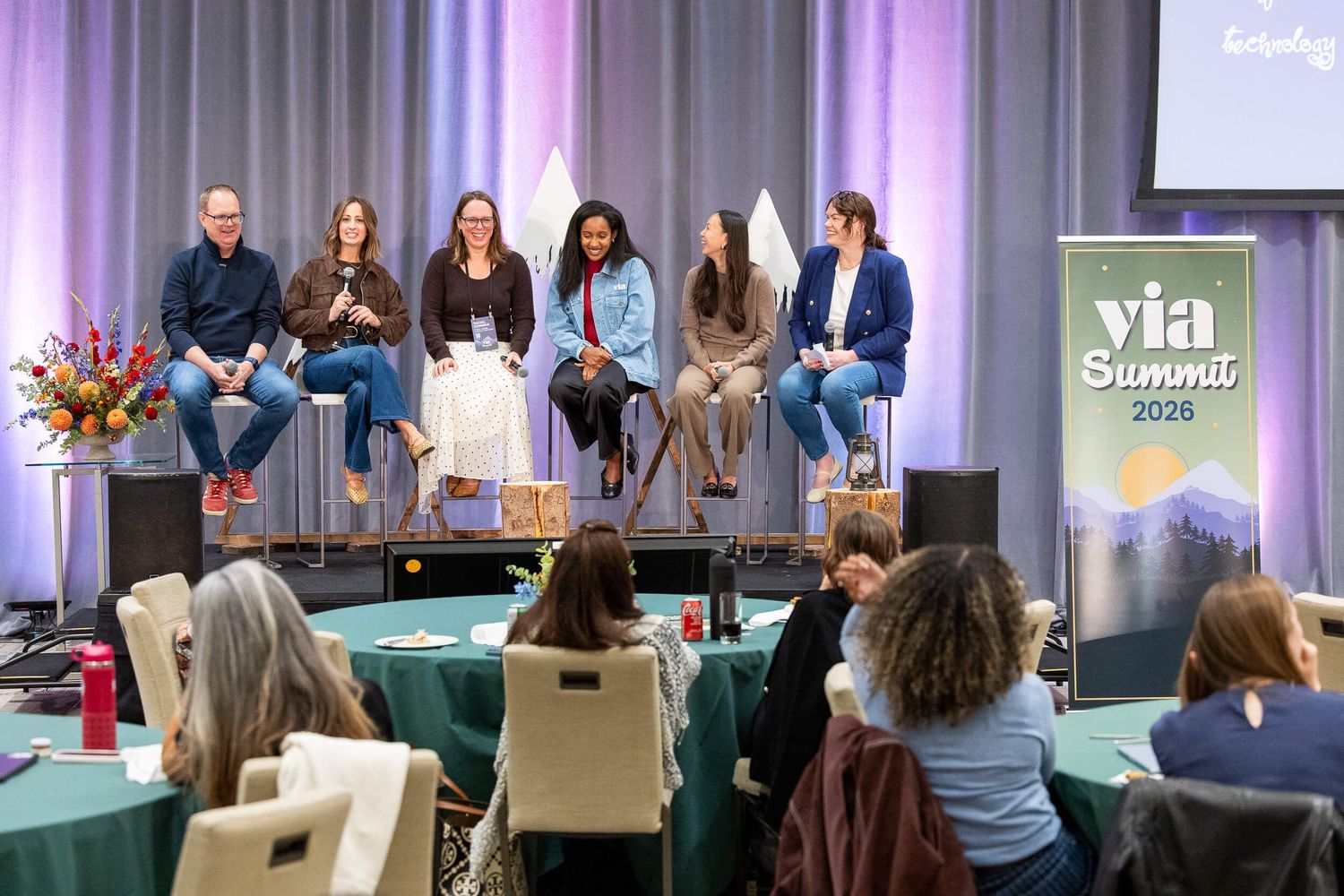 Panel of six speakers on stage at the VIA Summit 2026 summit in a purple-lit ballroom at the JW Marriott Parq Vancouver