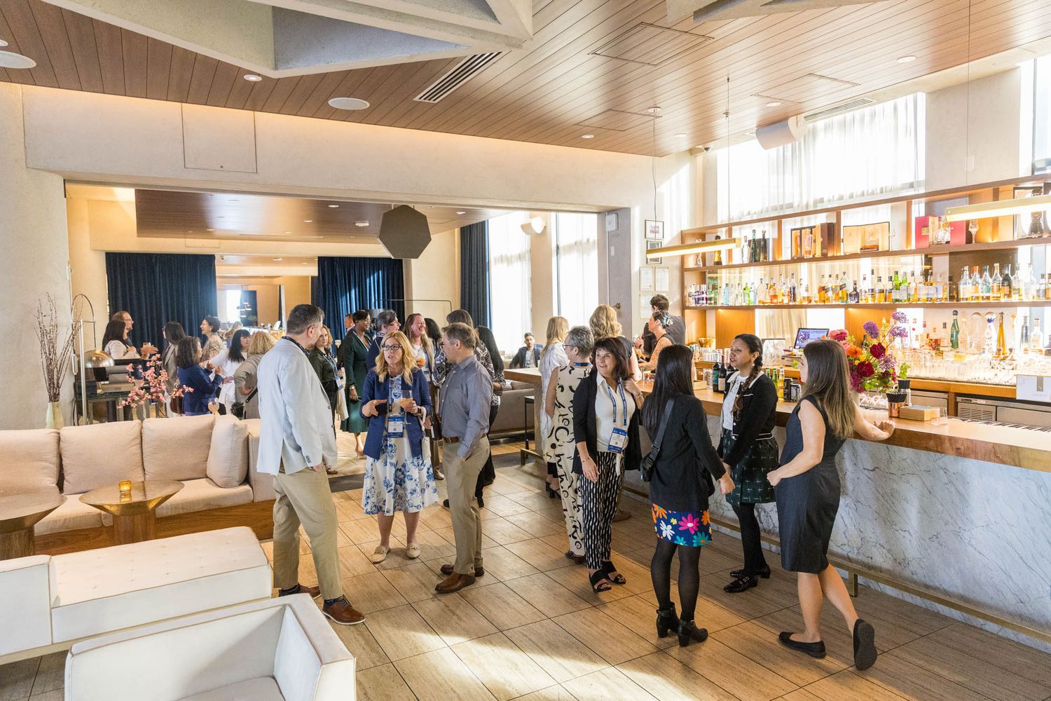 Guests mingle at a modern bar and lounge during a lively social event with warm lighting and stylish decor.
