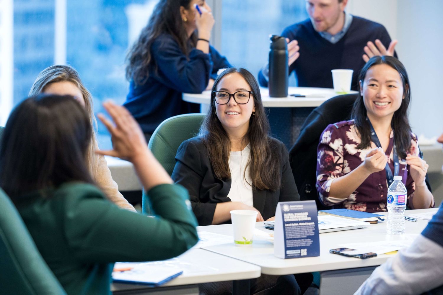 Diverse group of professionals engaged in lively discussion at a conference table in a modern office setting.