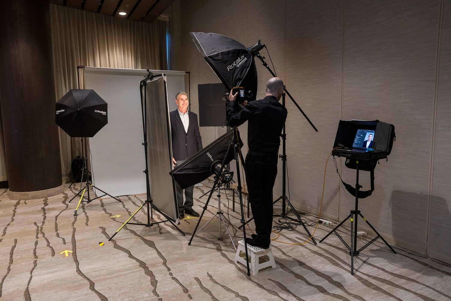 Professional photographer taking a portrait photo of a businessman in a studio setup with softbox lights.