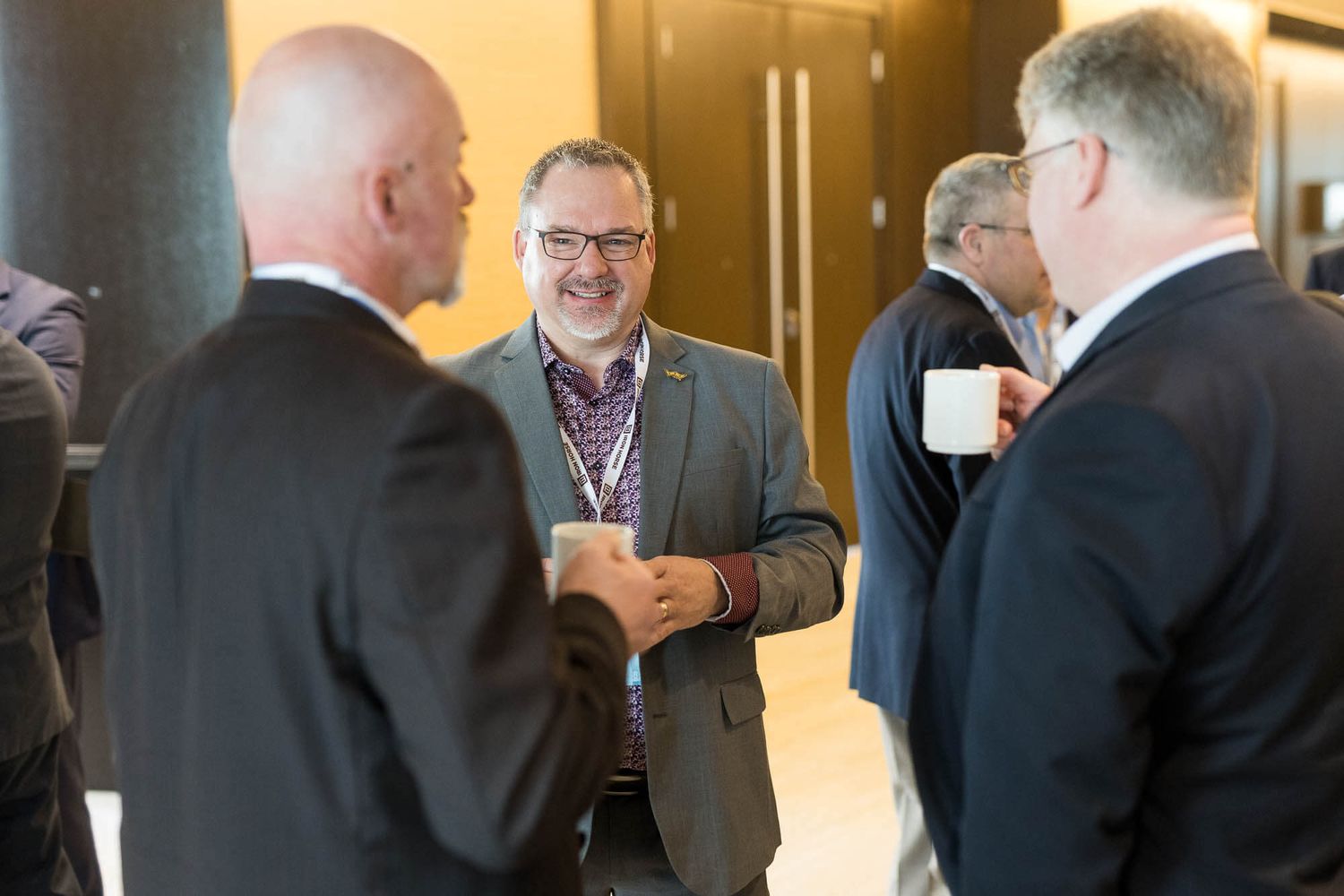 Business professionals networking and conversing at a corporate conference event indoors held at the JW Marriott Parq Vancouver.