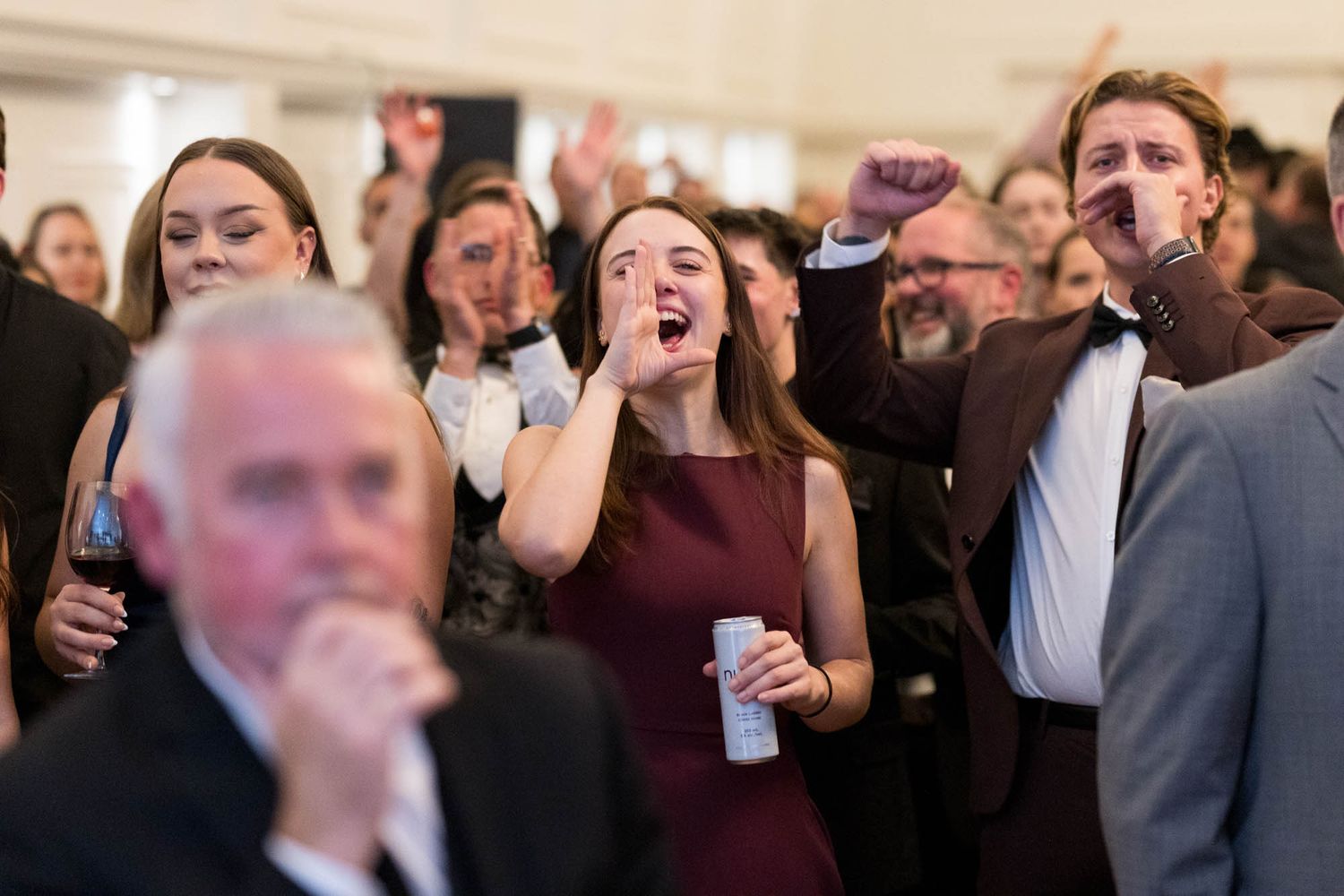 Excited crowd of guests celebrating and cheering at an Oscars viewing party event.