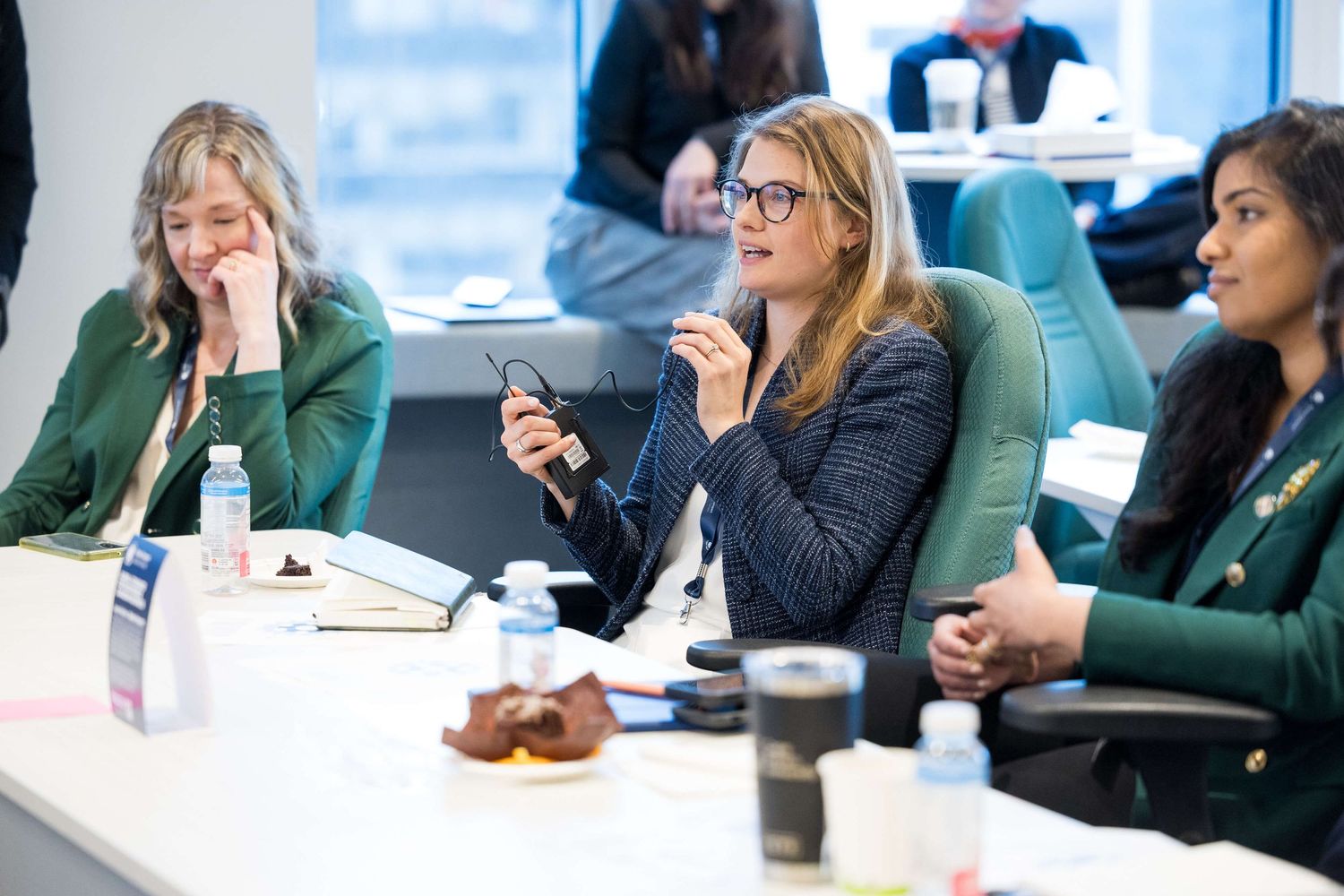Three professional women engaged in a business meeting discussion at a conference table in a modern office.