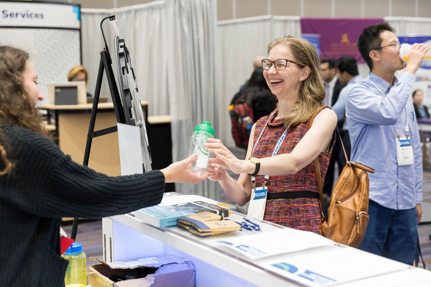Woman smiling while receiving a water bottle from a vendor at the Vancouver Convention Centre.