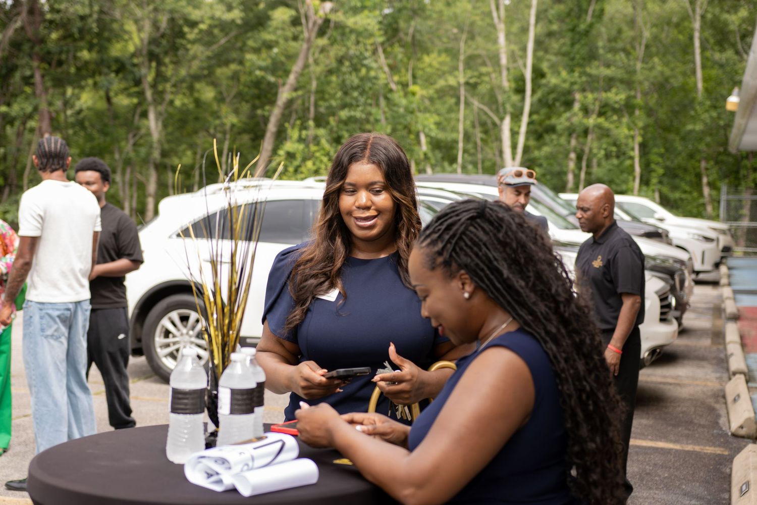 Two women networking at an outdoor business event, smiling and engaging in conversation at a round table.