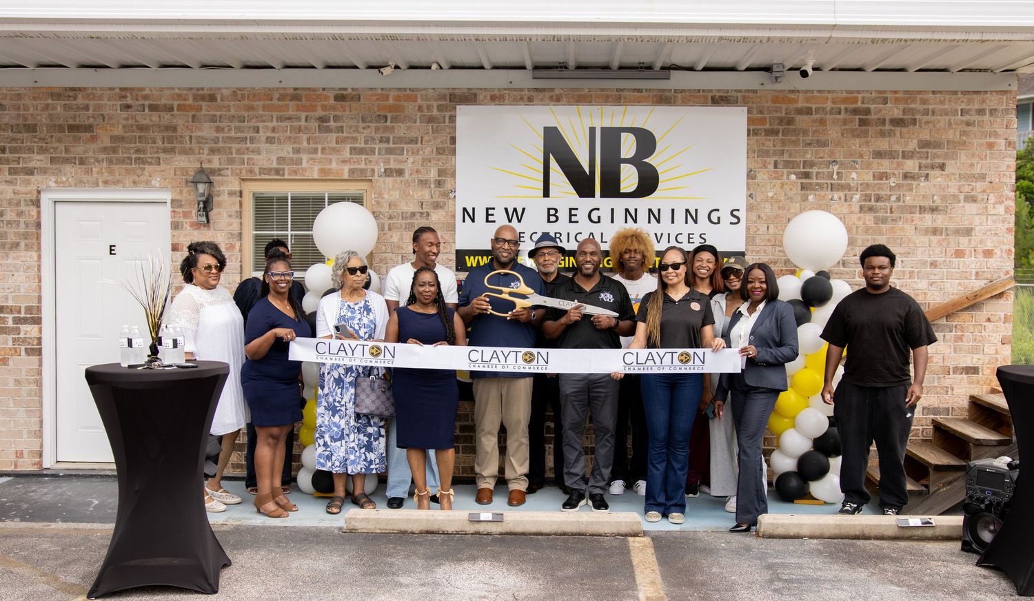 Ribbon cutting ceremony at New Beginnings grand opening with staff and officials posing outside brick building.