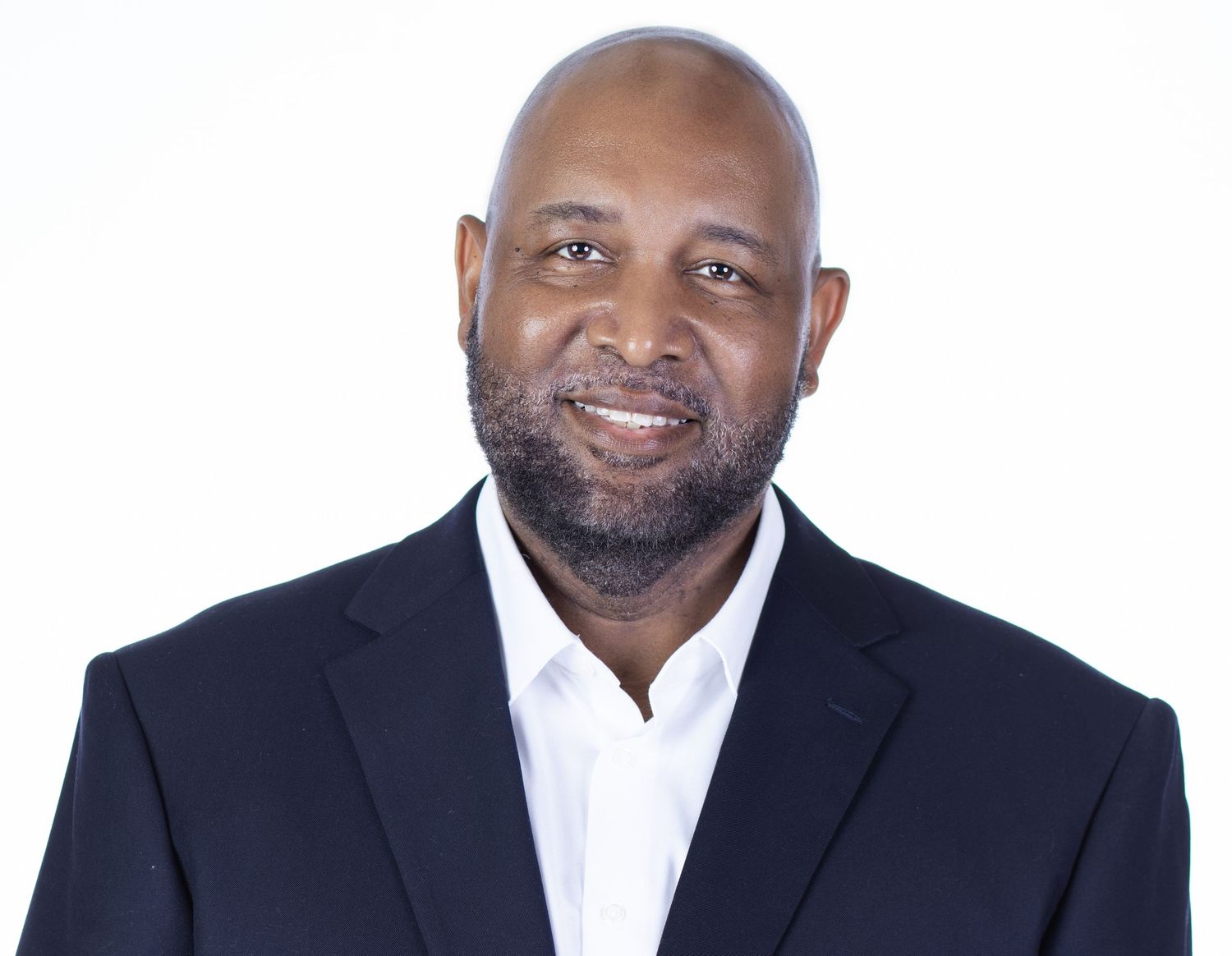 Professional headshot of a smiling man in a dark blazer and white shirt against a white background.