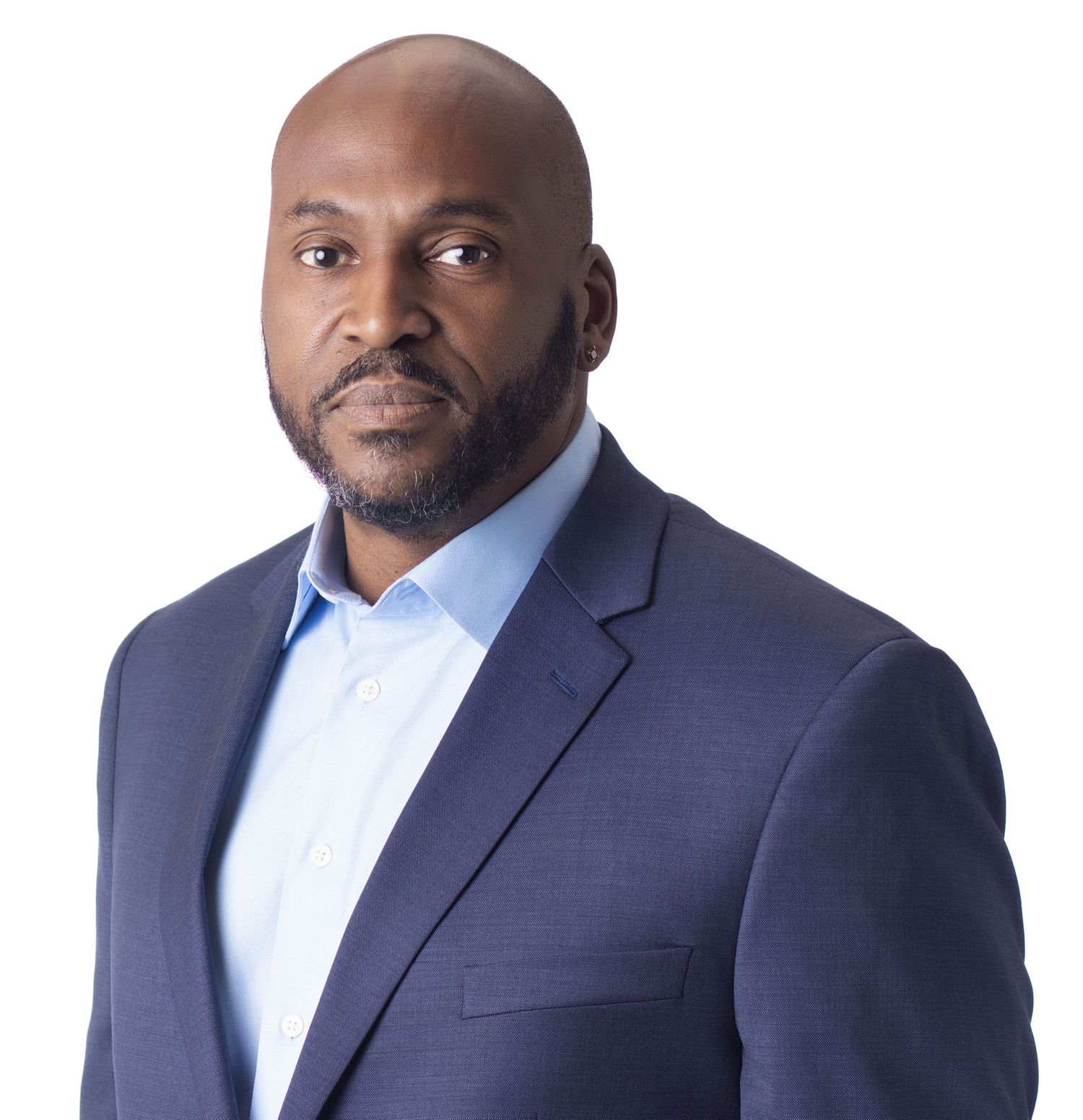 Professional Black man in navy blazer and light blue shirt poses confidently against white background.