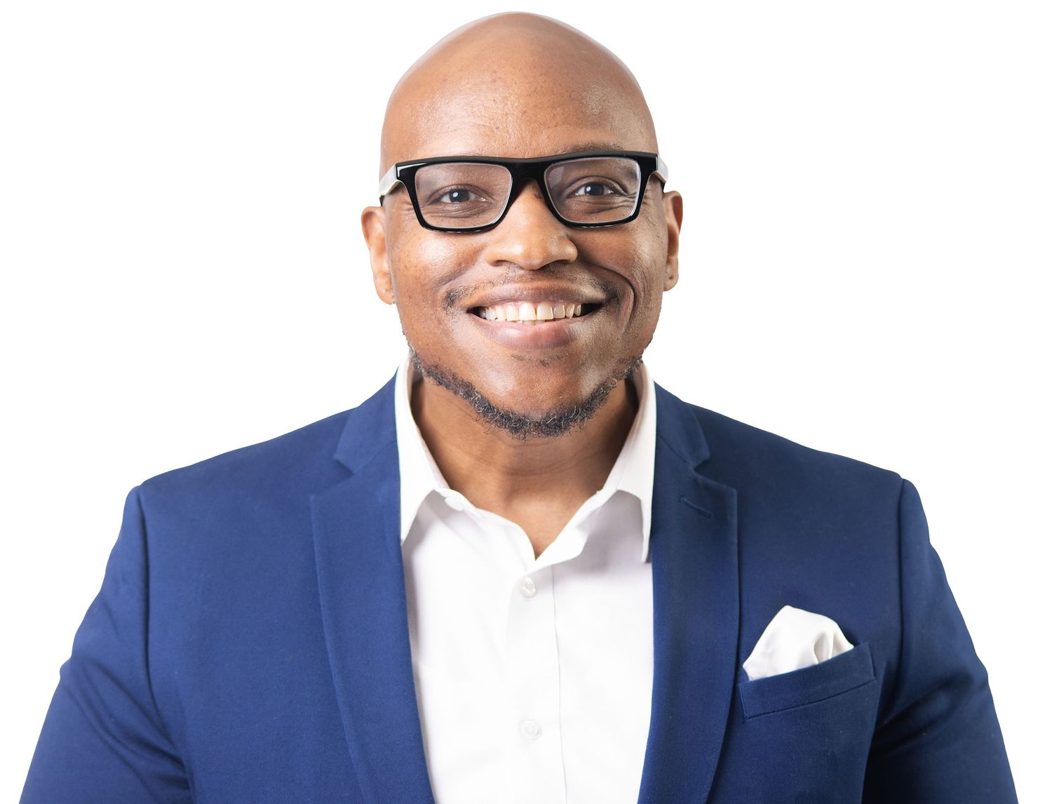 A smiling bald Black man wearing black glasses and a blue blazer with a white dress shirt and pocket square.