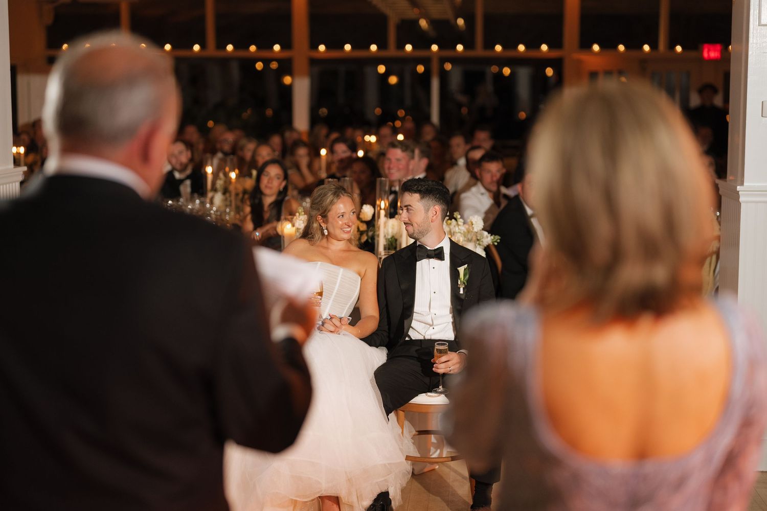 A wedding reception venue with guests seated at tables during dinner service.