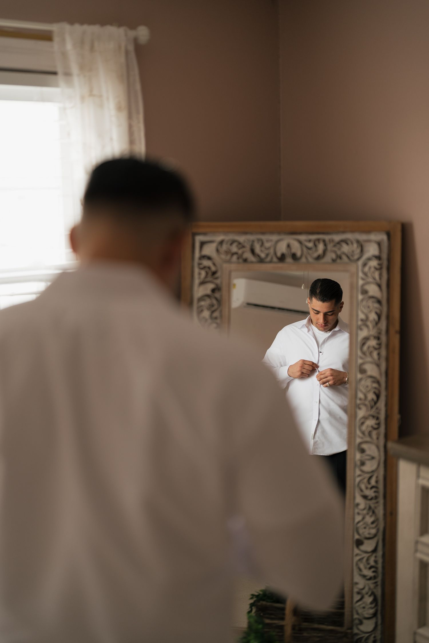 A sequence of four photos showing someone adjusting their tie and getting ready in front of a decorative framed mirror.