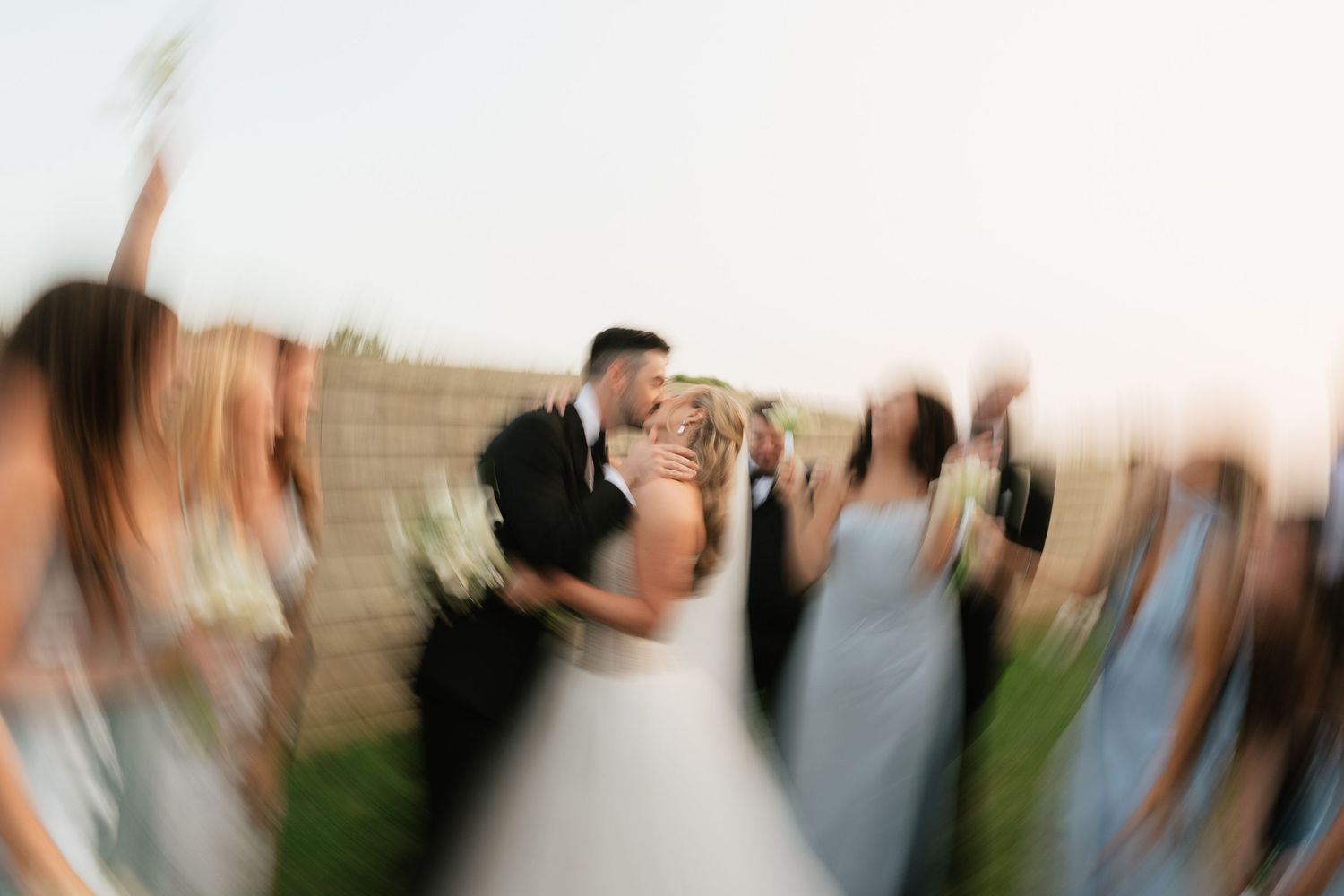 Motion-blurred wedding celebration with guests dancing at an outdoor venue.