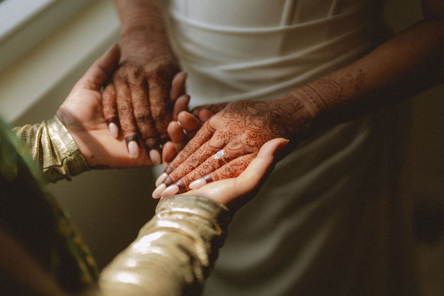 Close-up of hands adorned with henna mehndi designs during a traditional South Asian wedding ceremony.