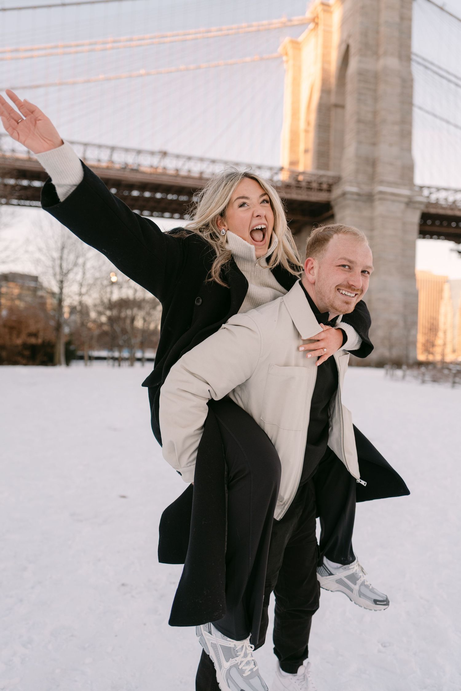 Playful couple in winter coats posing in the snow.