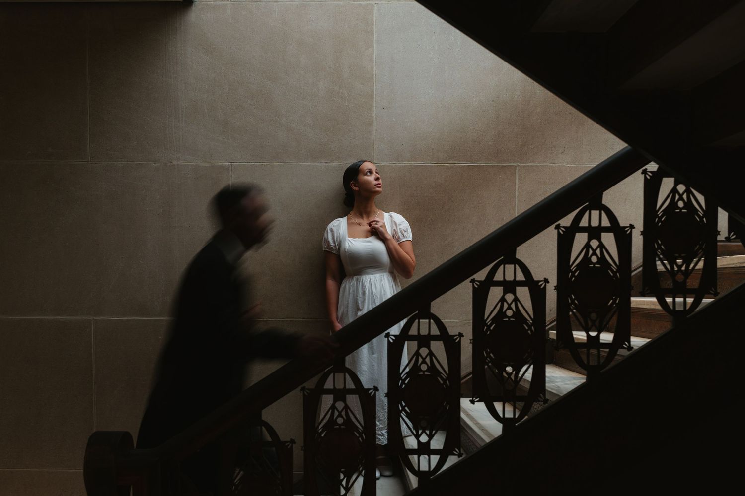 An intimate moment captured through architectural details in a stairwell with natural lighting.