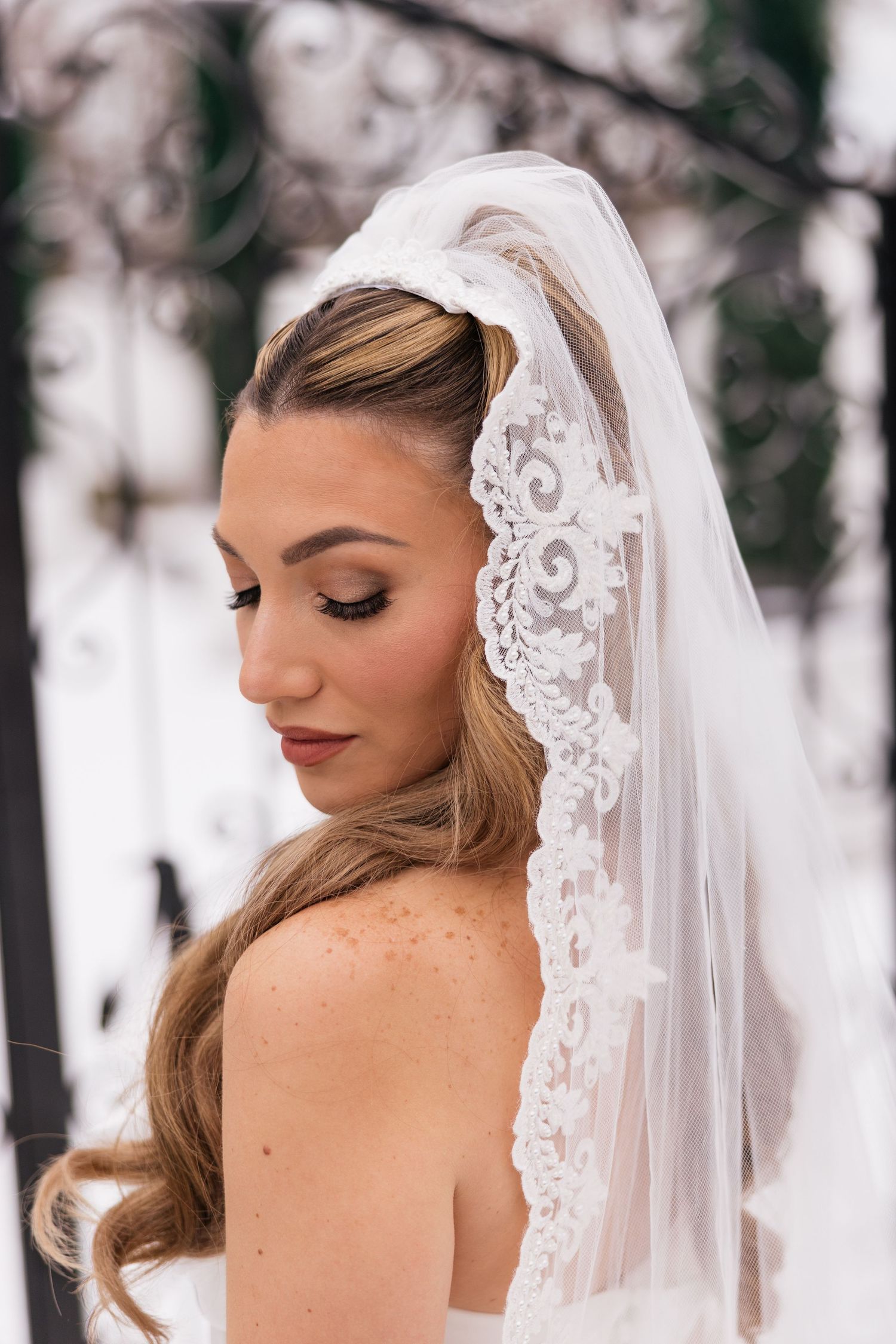 Close-up bridal portraits showing elegant lace veil details against a winter backdrop.