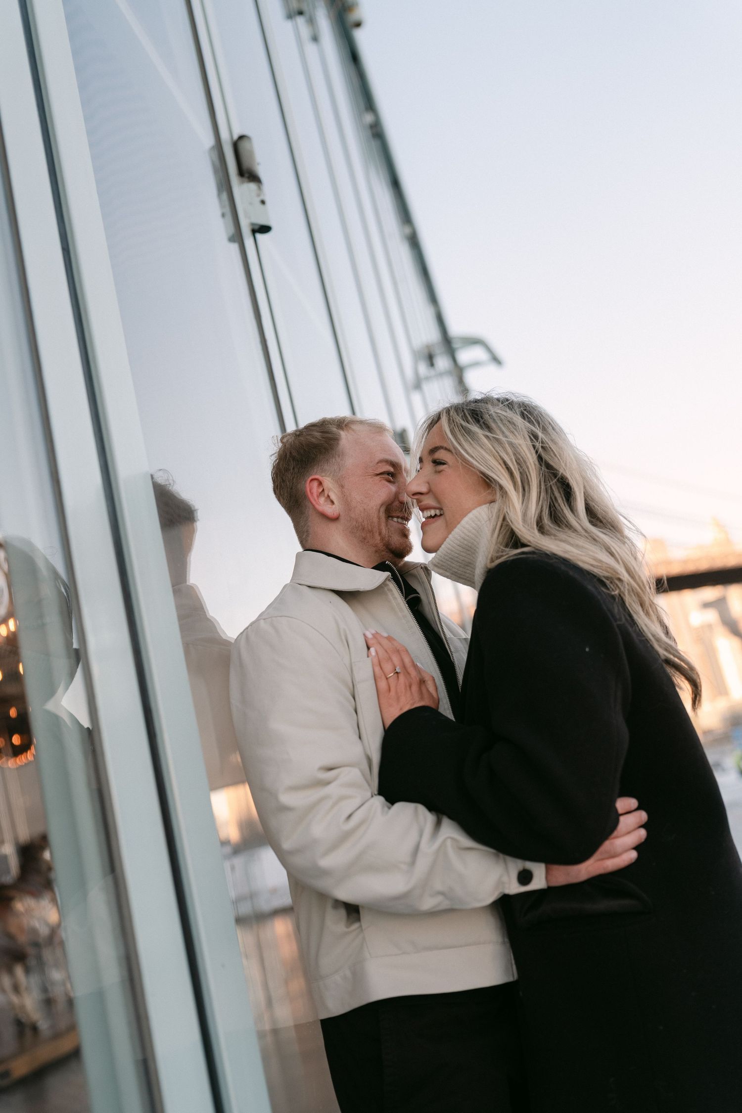Romantic winter photoshoot near glass building at sunset.