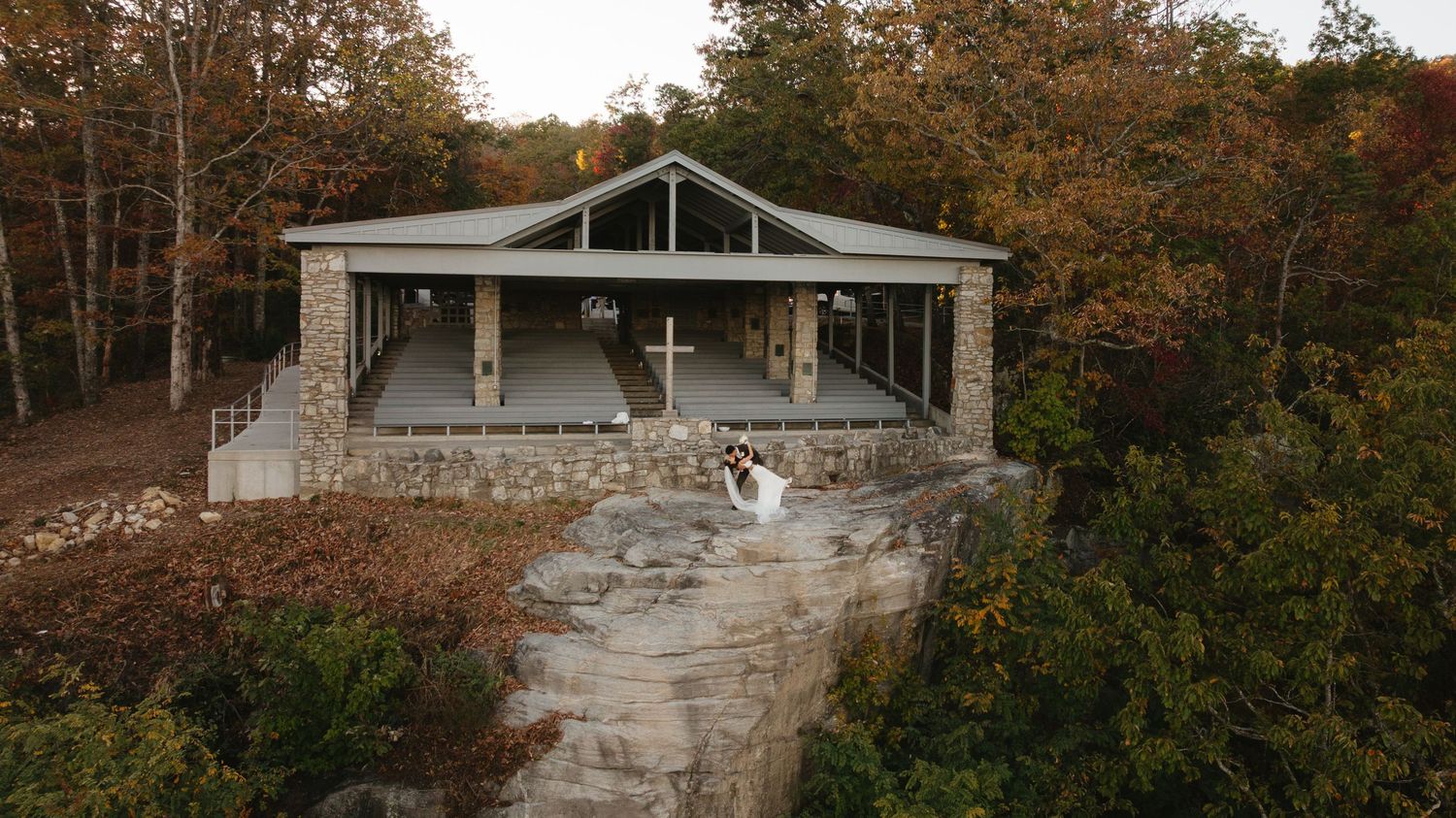 Modern architectural home nestled among autumn trees on a hillside property.