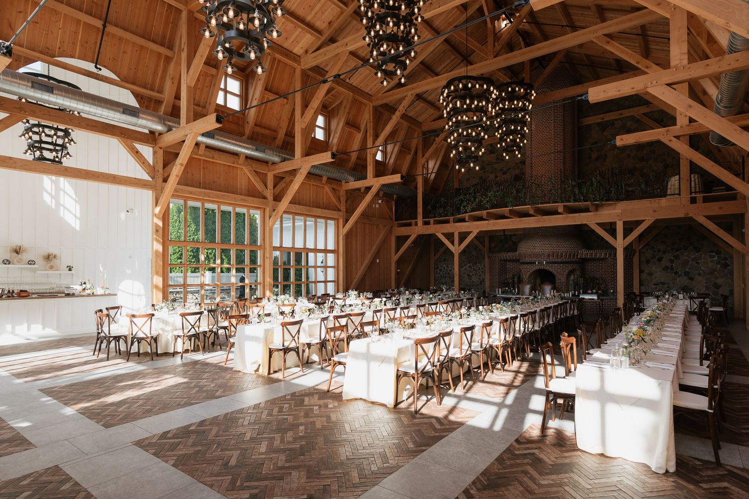 Rustic wooden barn venue interior with exposed beams and elegant chandeliers illuminating the open event space.