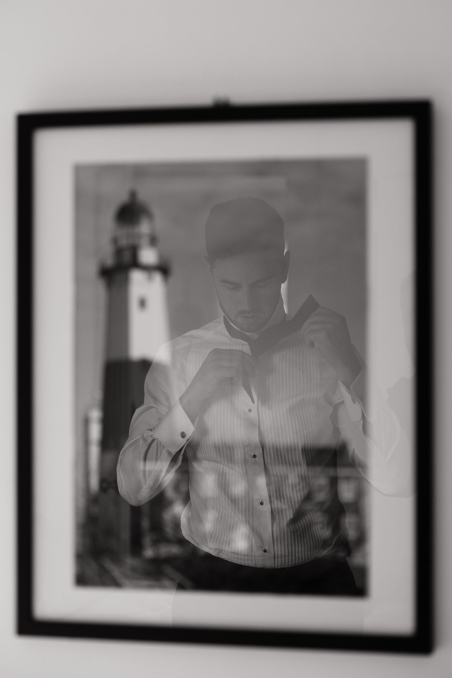A black and white framed photograph shows a person in a button-down shirt with a lighthouse in the background.