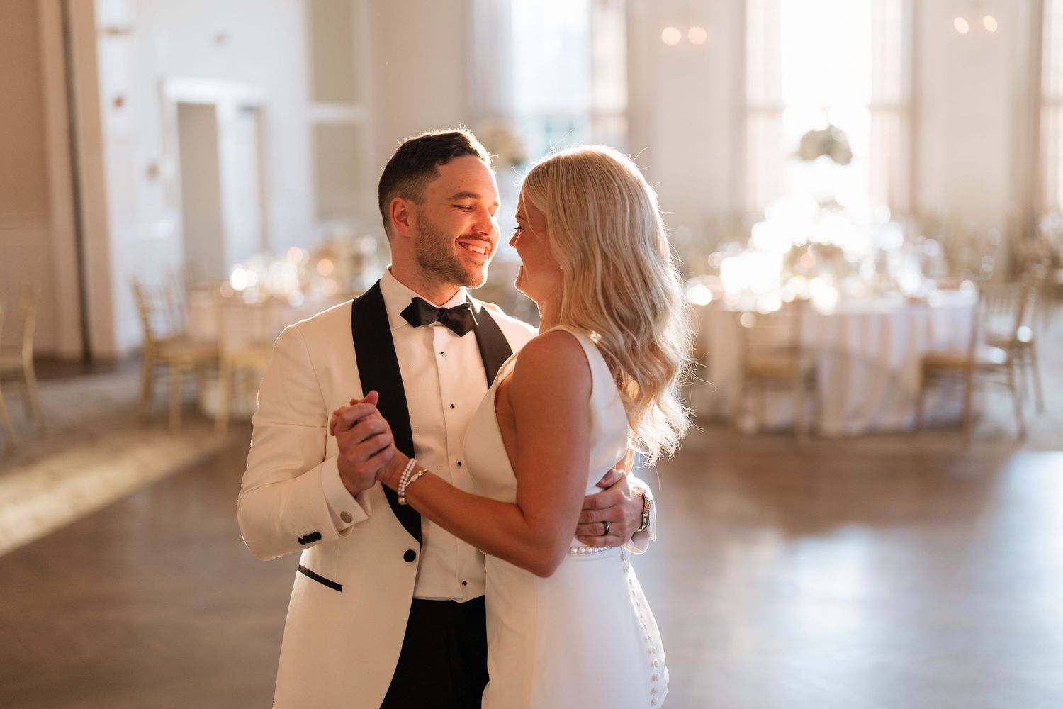 Elegant couples dancing together in a bright ballroom during a formal wedding celebration.