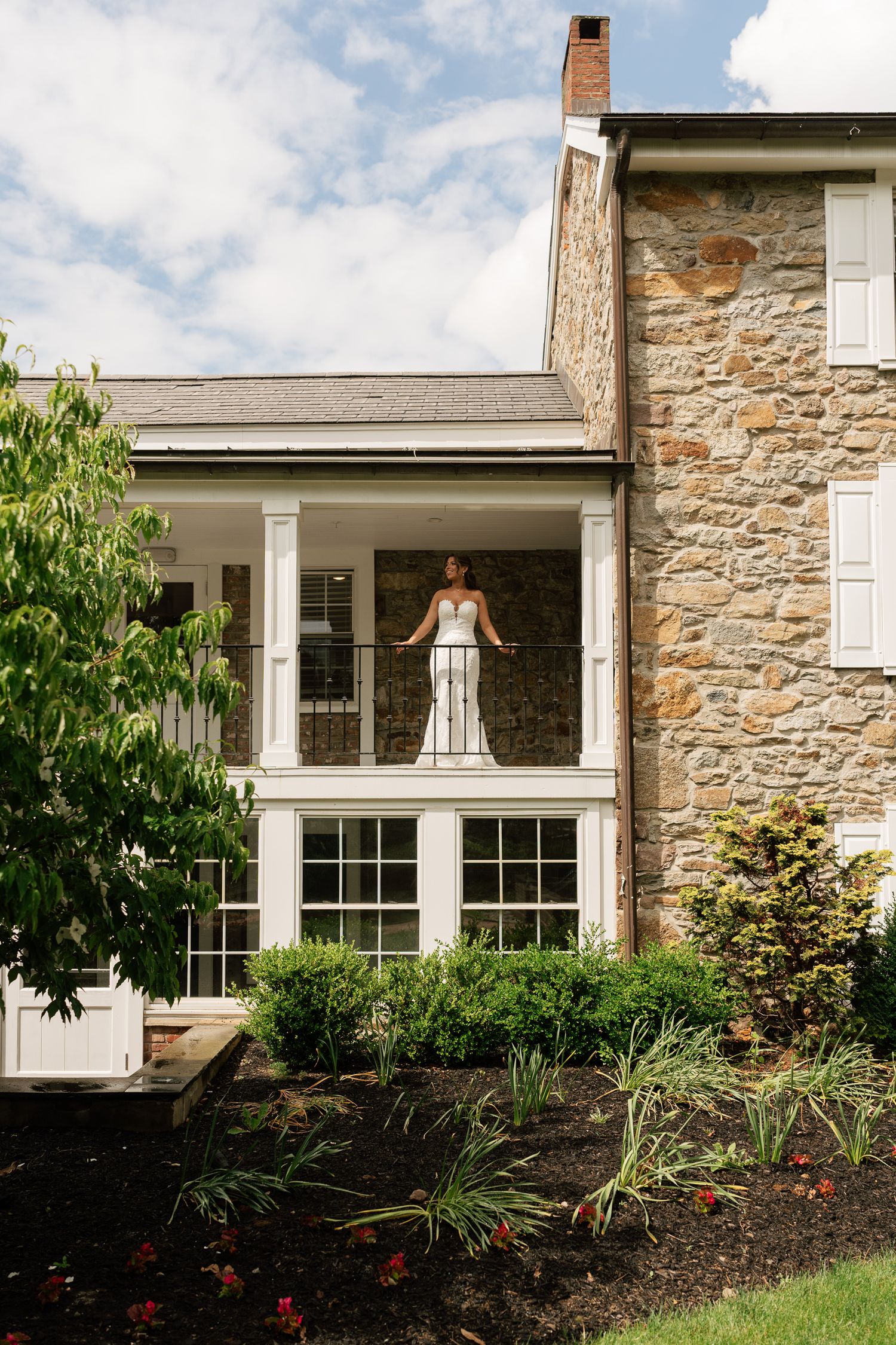 Stone facade of an elegant country home with white trim and landscaped gardens.