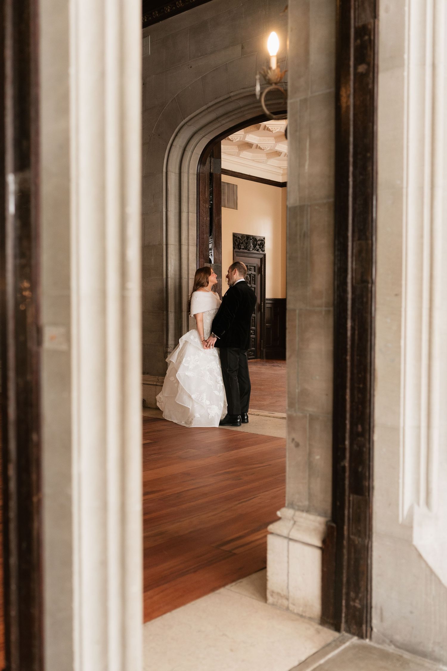A dramatic hallway with white columns and hardwood floors showcases a bride in a flowing gown.