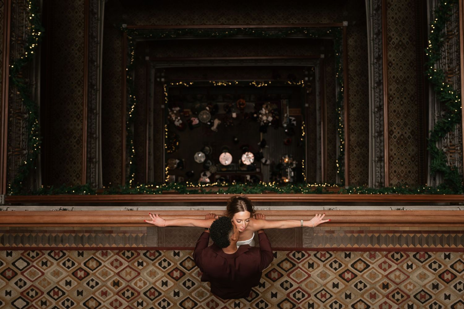 Couple shares an intimate moment in an elegant dark venue with decorative lighting.